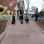 新業(yè)建設(shè)卓勝隆董事長(中)與來賓童心大發(fā)，一起玩溜滑梯。