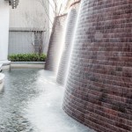 與接待大廳相對(duì)，僅隔一道玻璃落地窗即為「戶(hù)外水瀑牆」。流水潺潺與磚石沖刷出平整的紋路，水光相映下霧氣生騰，彷若仙境。－【新業(yè)觀峰】。