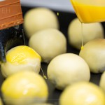 刷上蛋黃液，點(diǎn)上芝麻裝飾，圓潤(rùn)蓬鬆的蛋黃酥即將穿上金黃酥脆的外衣。