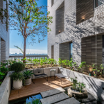 四季合院，每三層設(shè)計(jì)一處公共大露臺(tái)，從梯廳走入彷彿大家庭的合院(埕)，提供住戶們休憩及交誼空間，搭配四季主題的呼應(yīng)，此為七樓的夏季-種植小花紫薇與厚葉石斑木。