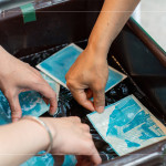 將明信片輕放入水箱中，清洗掉藥水後，隨著雙氧水的洗禮，藍(lán)曬圖像逐漸浮現(xiàn)。