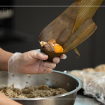 將粽葉三分之一處折起，交叉形成漏斗狀，轉(zhuǎn)著處末端折一個(gè)折角，再將內(nèi)餡包入。