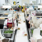 新業(yè)同仁與甘霖志工們分工合作，以生產(chǎn)線的方式有序地進行，將熱騰騰的餐食迅速裝盒，確保長輩能準時享用午餐。